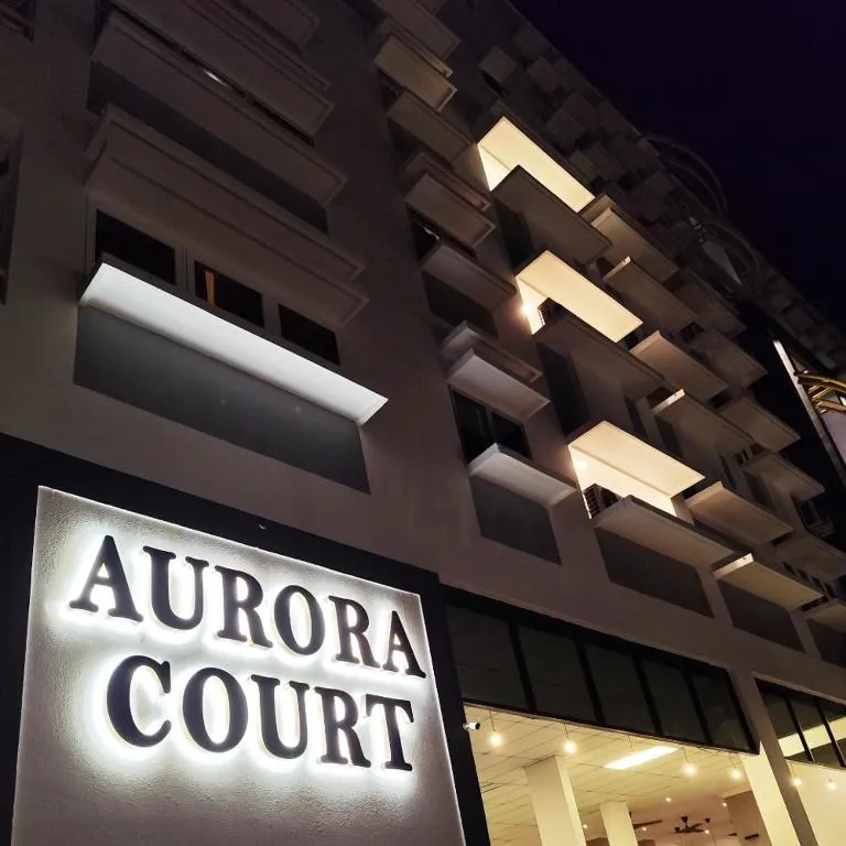 Aurora Court's illuminated sign beneath the building's balconies at night