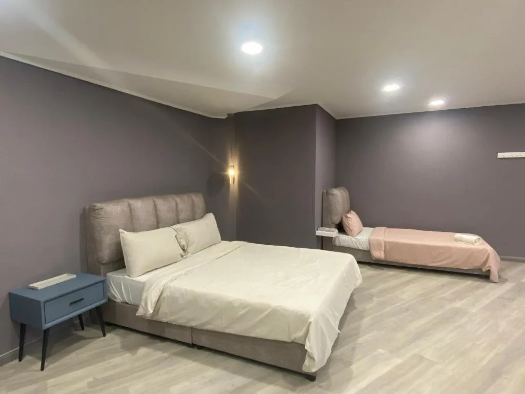 Studio with a queen bed and a single bed against grey walls
