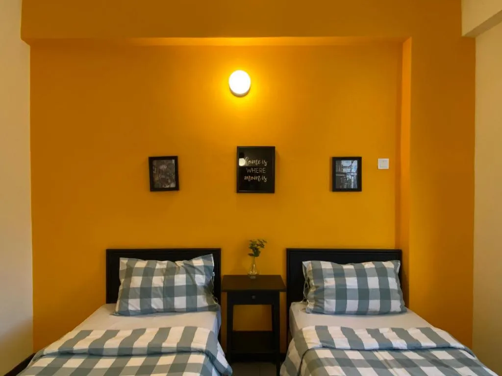 Twin room with mustard-yellow feature wall