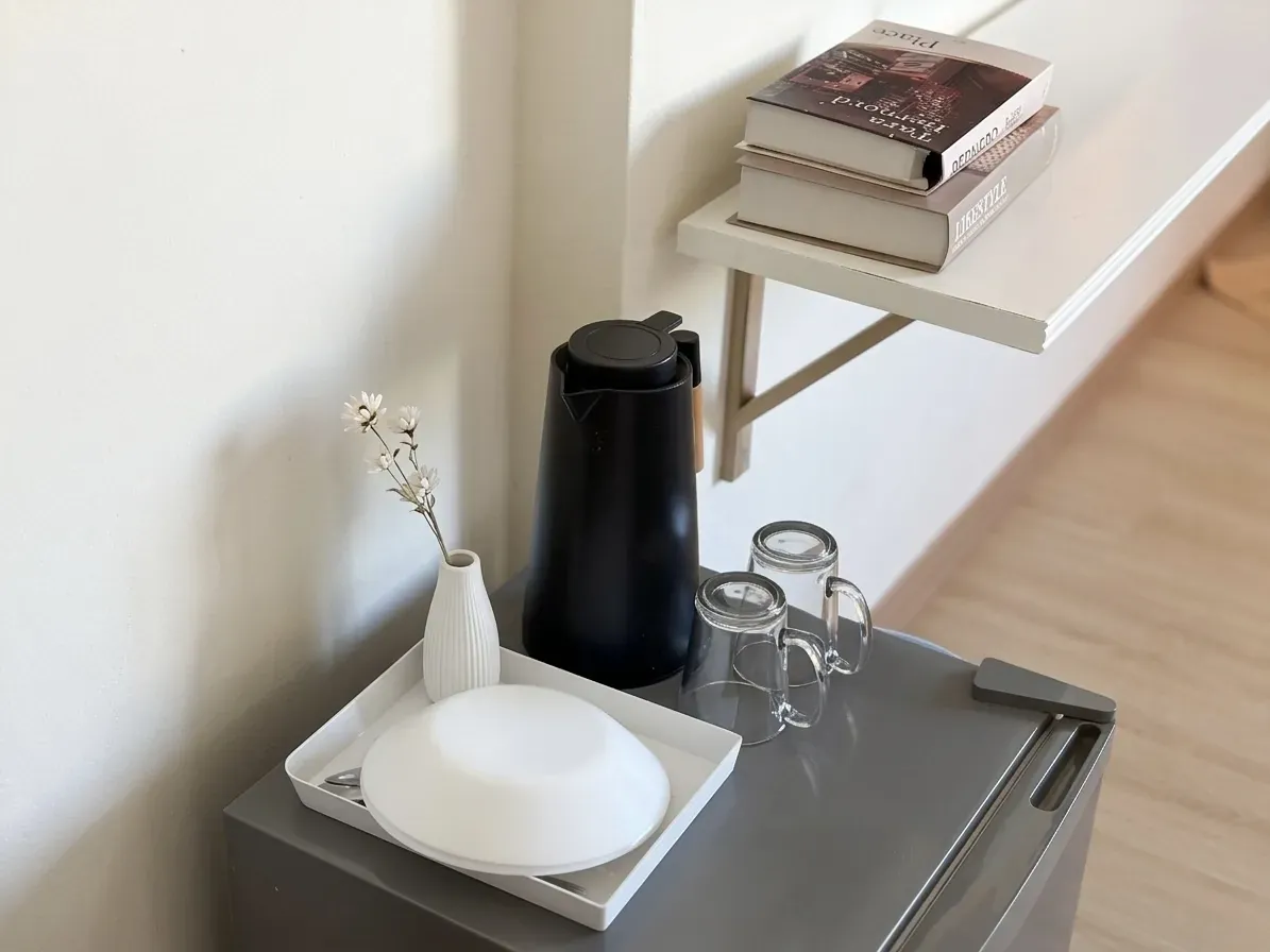 Kettle, glasses and fridge beneath a wall shelf