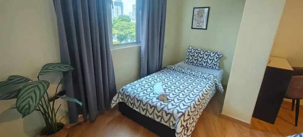 Double bed beside tall windows and curtains