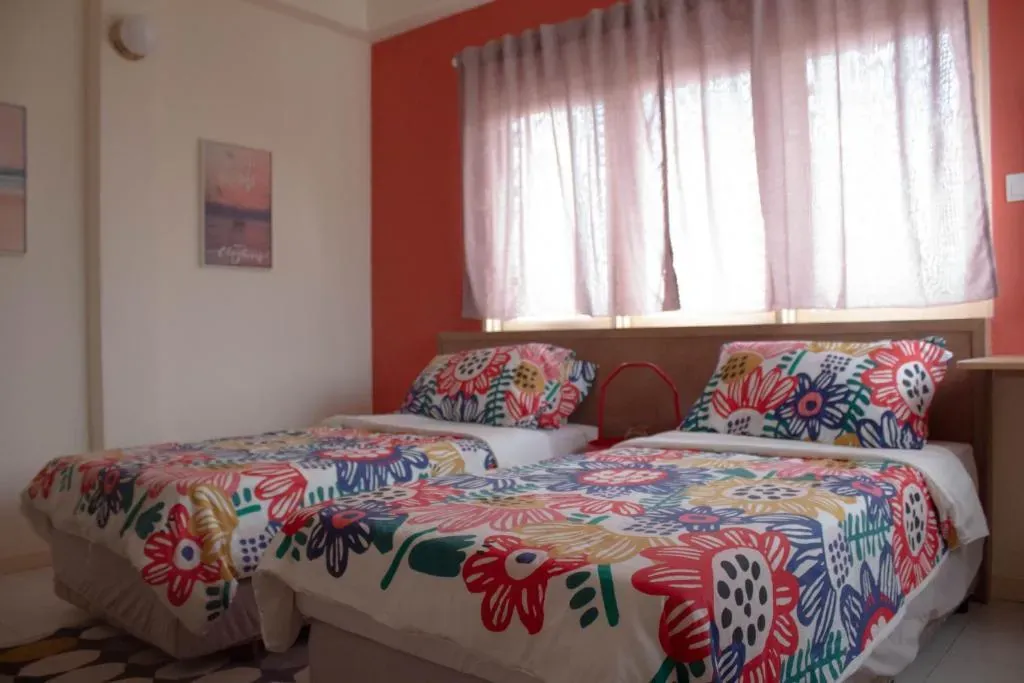 Two single beds with floral bedding under a sunny window