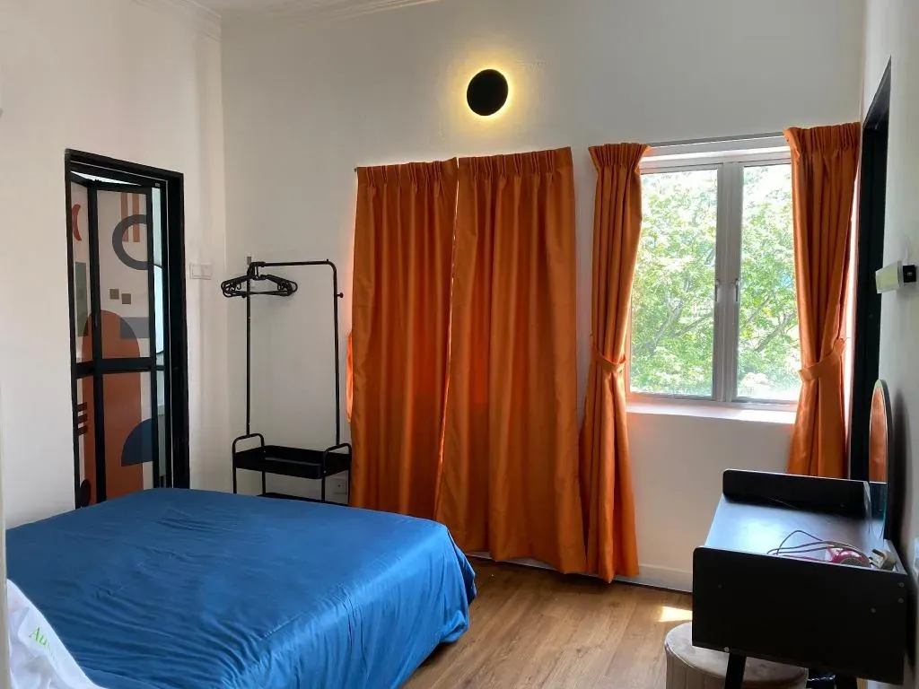 Bedroom with orange curtains and clothes rail