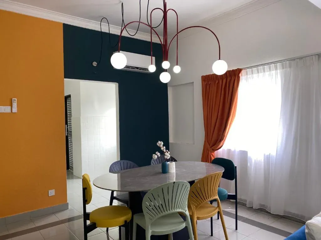Dining table with colourful chairs beneath a chandelier